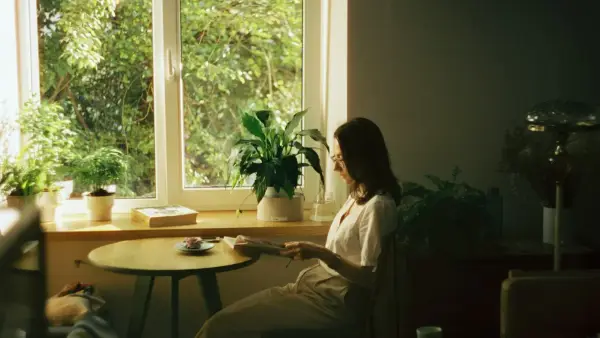 woman in white dress shirt sitting on chair near window during daytime