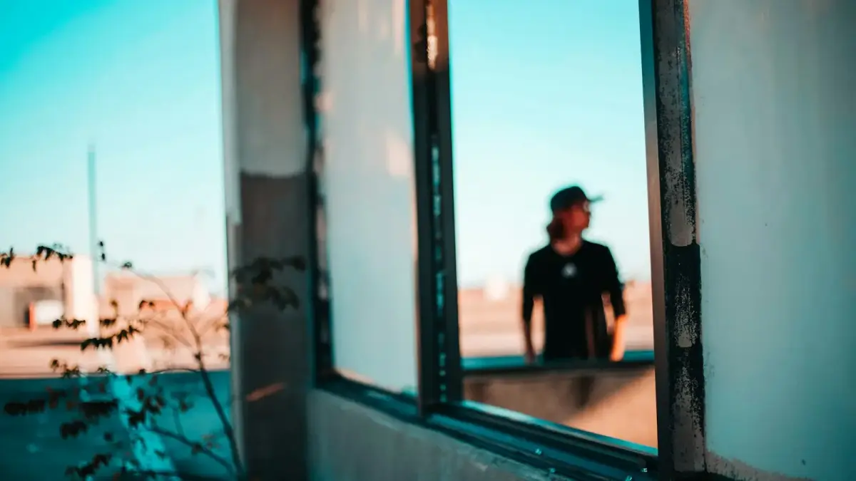 man in black shirt standing beside window during daytime