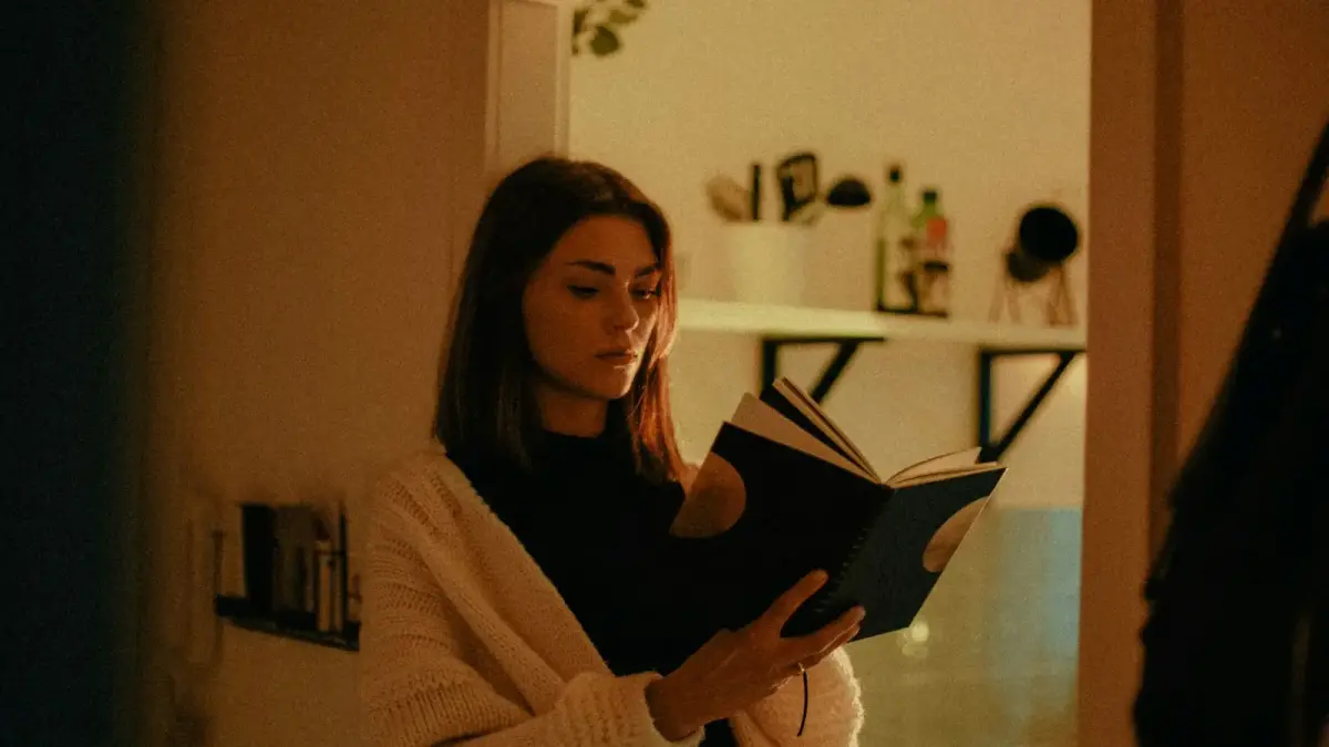 woman in white sweater holding book