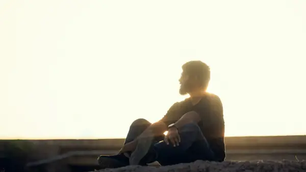 a man sitting on top of a rock near the ocean