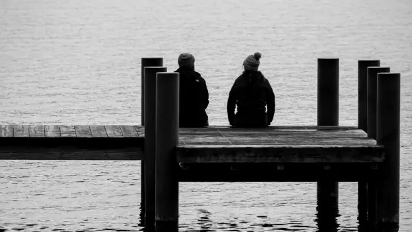 a couple of people sitting on top of a pier