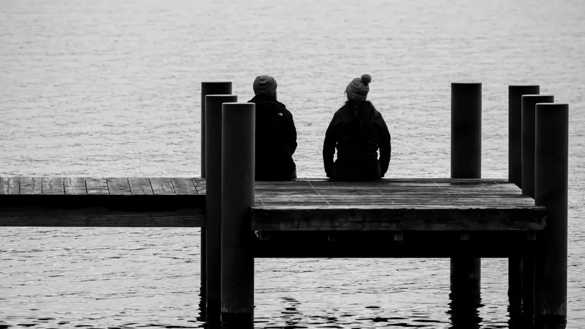 a couple of people sitting on top of a pier