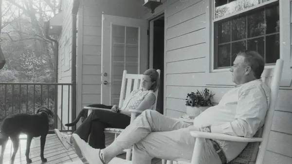 A couple and their dog relaxing on a porch.
