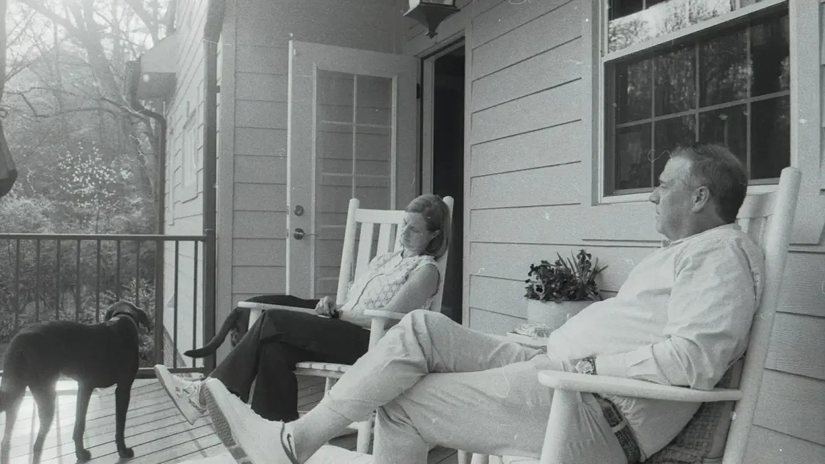 A couple and their dog relaxing on a porch.
