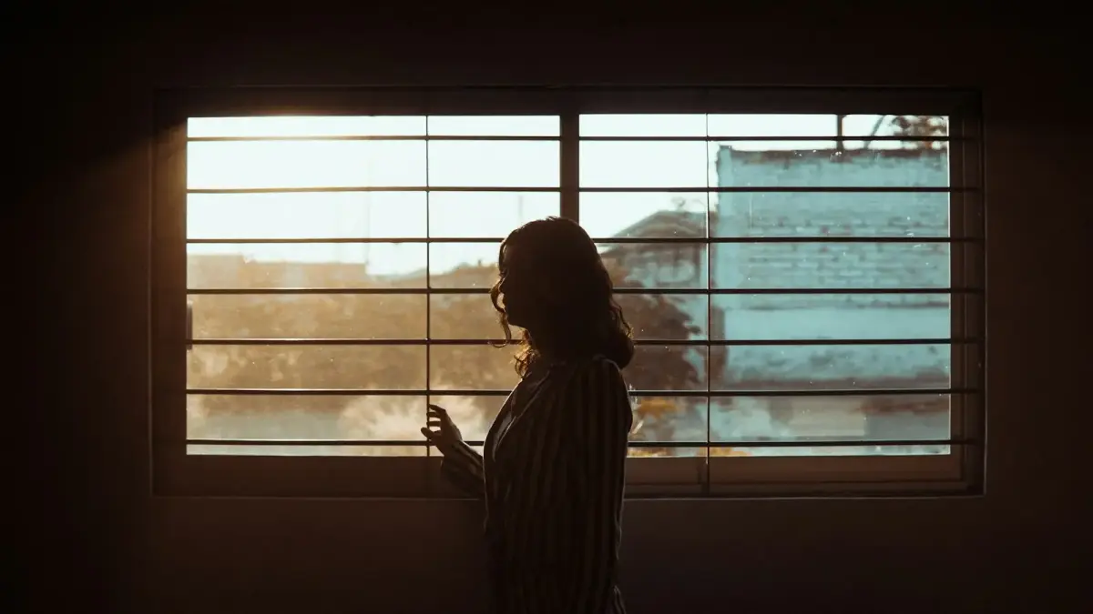 woman in white and black stripe shirt standing near window