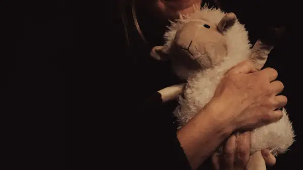 Woman hugging a stuffed sheep toy