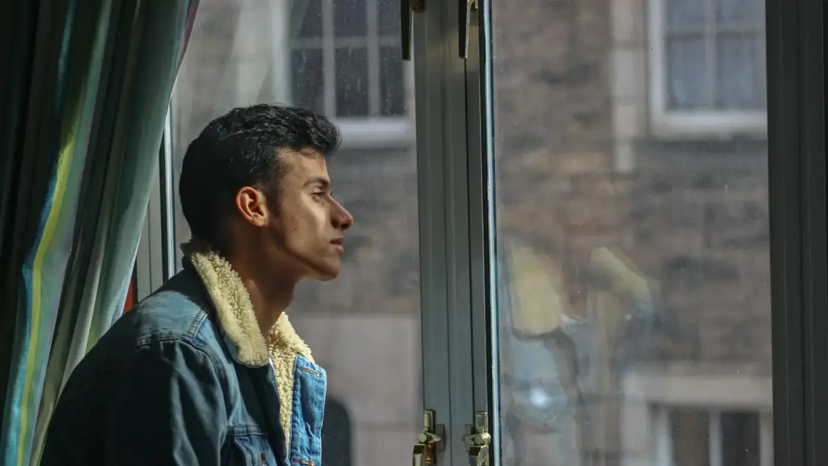 man in black jacket looking out the window