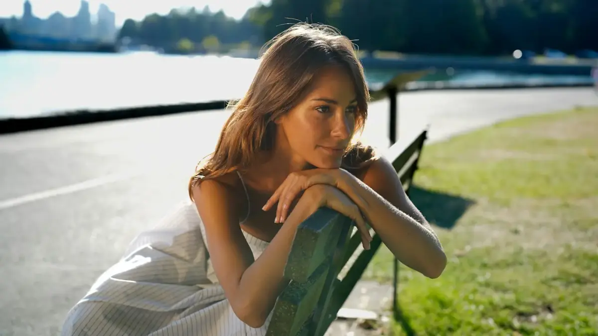 Woman rests head on arms on park bench