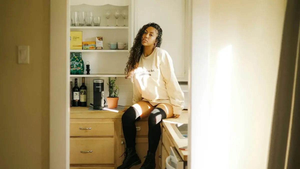 woman in white long sleeve shirt sitting on white wooden shelf