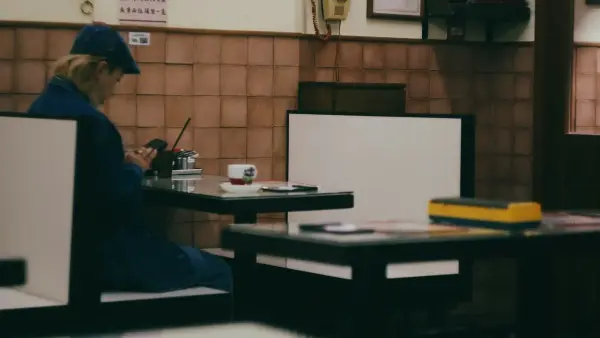 Solitary person in blue sits at a cafe table.