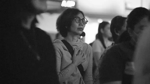 Woman in glasses with hand on chest looking away