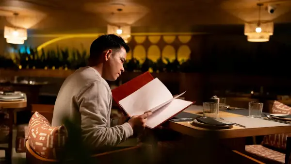 Man reading a menu at a restaurant table.