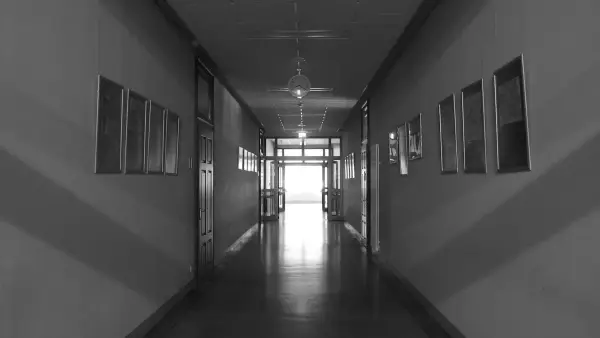 A long, empty school hallway with doors and windows