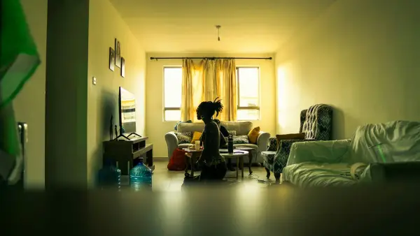 A person kneels in a dimly lit living room