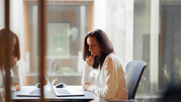 a woman sitting at a table with a laptop computer