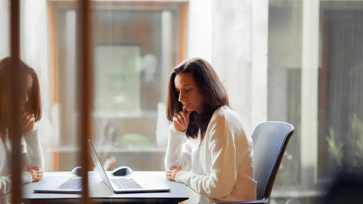 a woman sitting at a table with a laptop computer