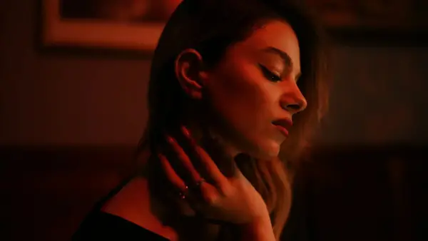 A woman with her hand on her neck in dim red lighting