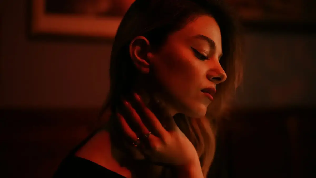 A woman with her hand on her neck in dim red lighting