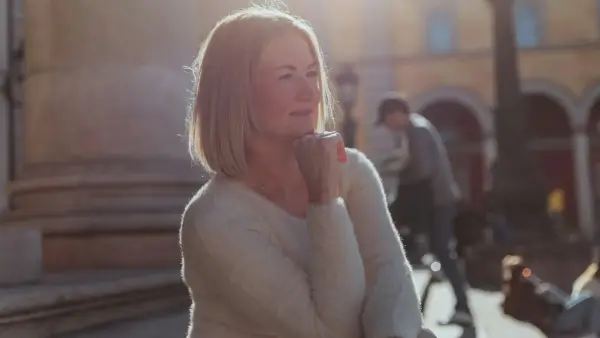 A woman standing on a sidewalk talking on a cell phone