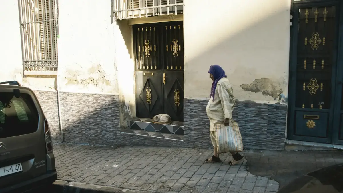 Woman walks past a building with a dog