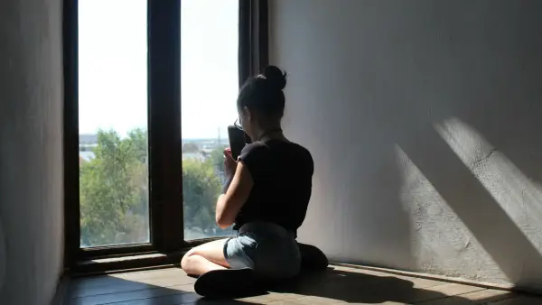 An older woman sitting alone in warm afternoon light, contemplative and dignified