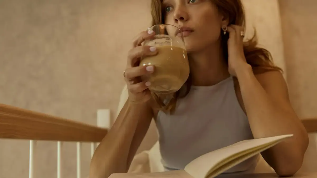 woman in white tank top drinking from clear drinking glass