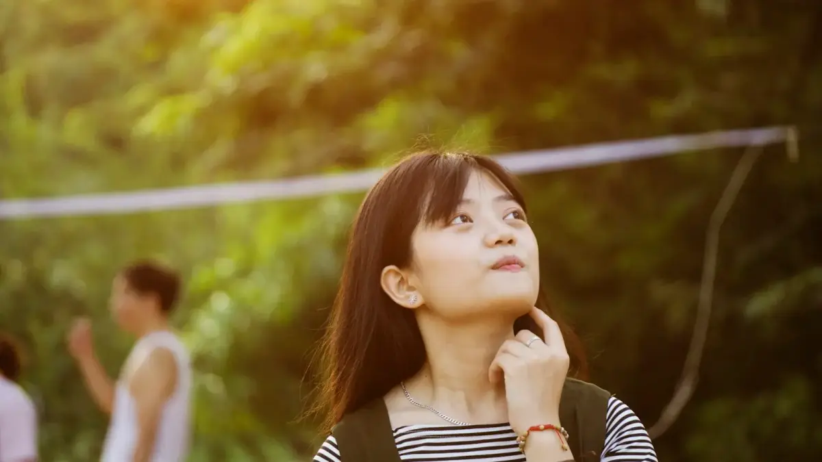 A woman sitting alone by a coffee shop window watching rain