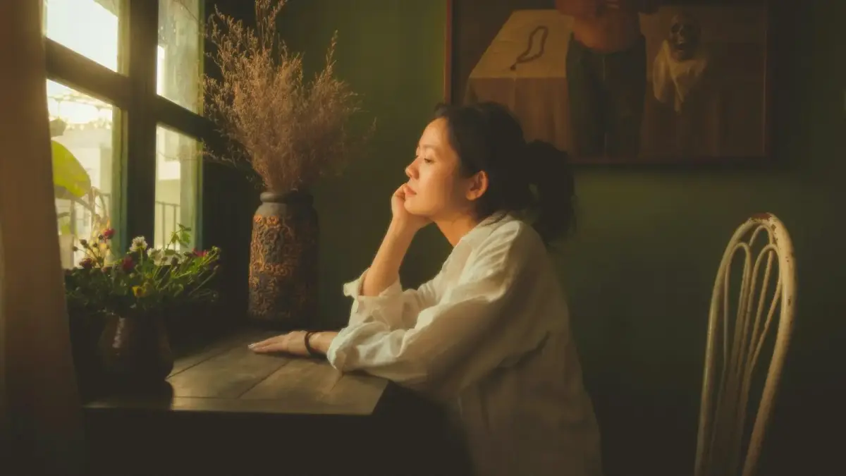 a woman sitting at a table looking out a window