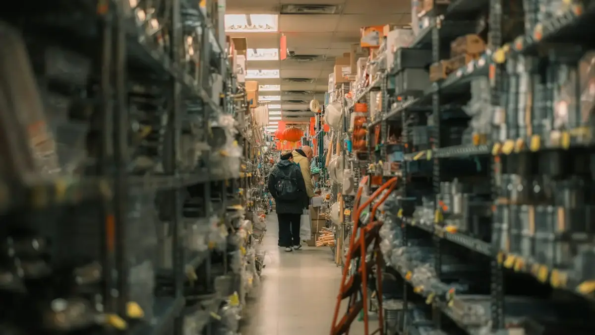 Person walks down aisle of stocked warehouse shelves