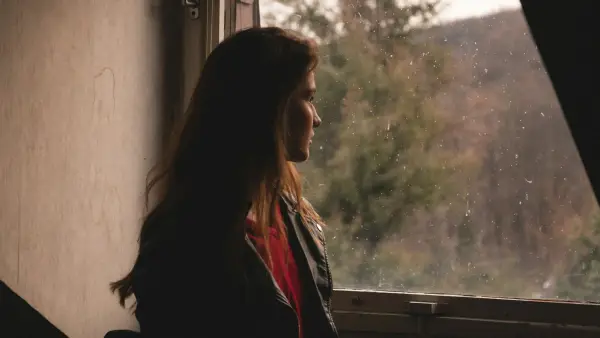 a woman standing in front of a window looking out