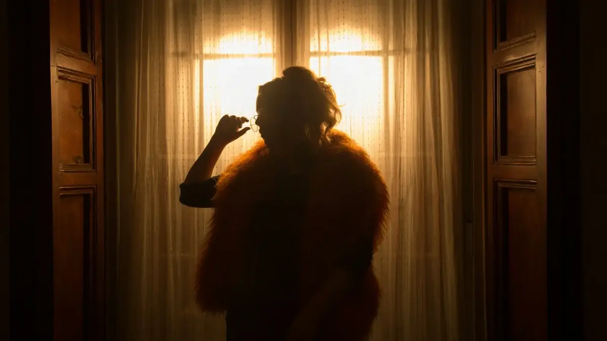 woman raising right hand while standing near curtain