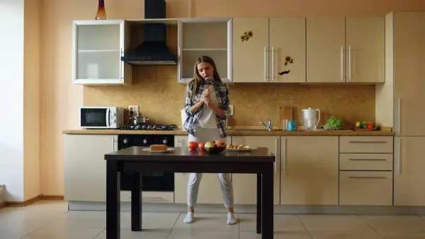 Young woman standing in a kitchen with apples on table.