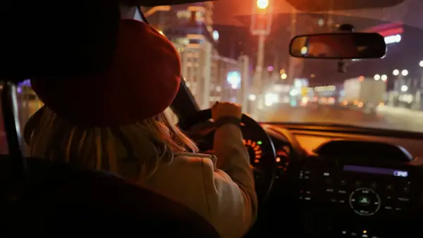 a woman driving a car at night on a city street
