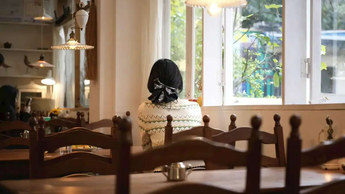 Woman sitting at a table by the window.