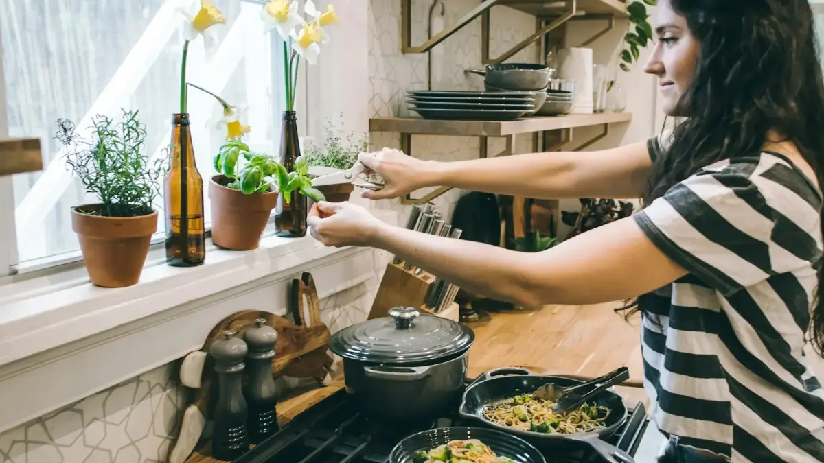woman standing in front of cooking range holding flower's leaves