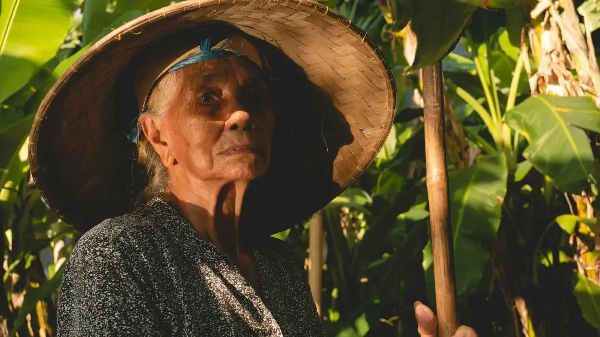 an old woman wearing a straw hat and holding a stick