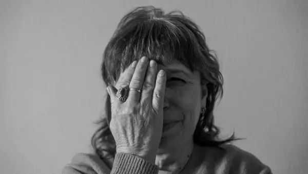 grayscale photo of woman covering her face with her hand