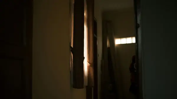 Sunlight streams through a doorway, illuminating curtains