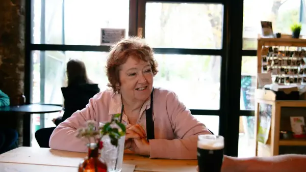 Elderly woman smiling at a table with beer