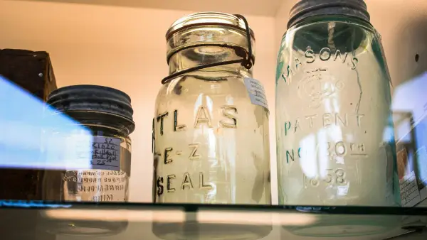 three glass jars are sitting on a shelf