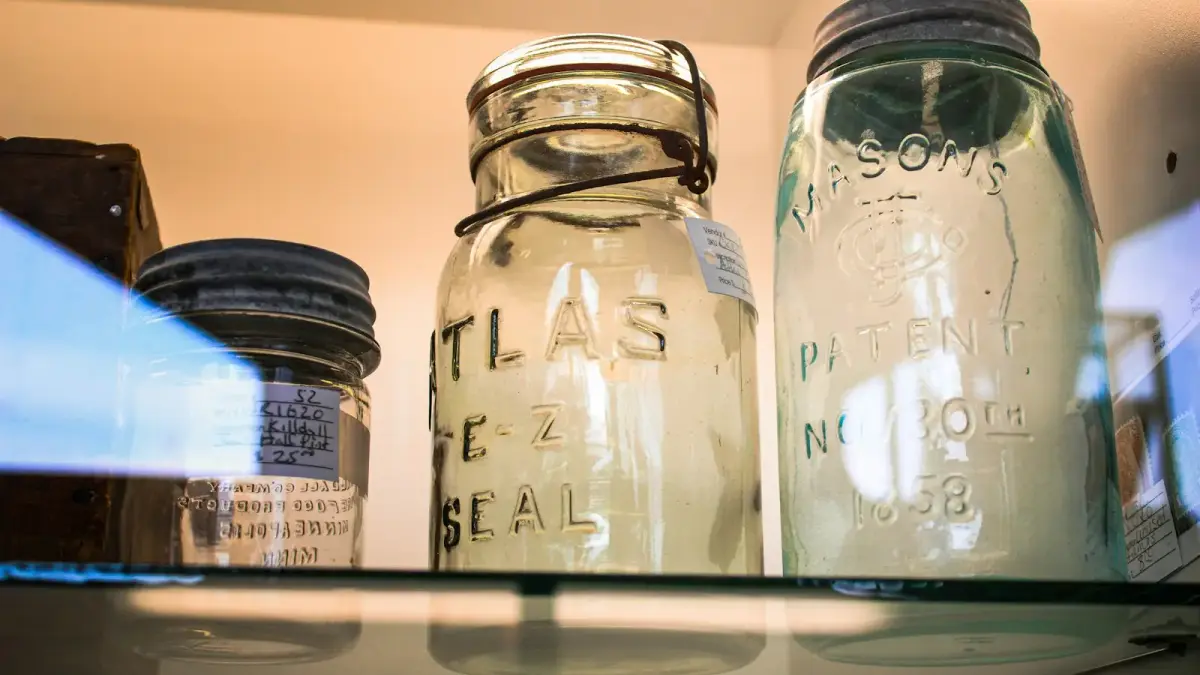 three glass jars are sitting on a shelf