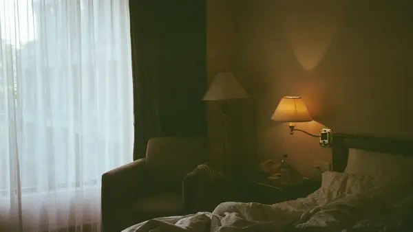 a bedroom with a bed, chair, lamp and window
