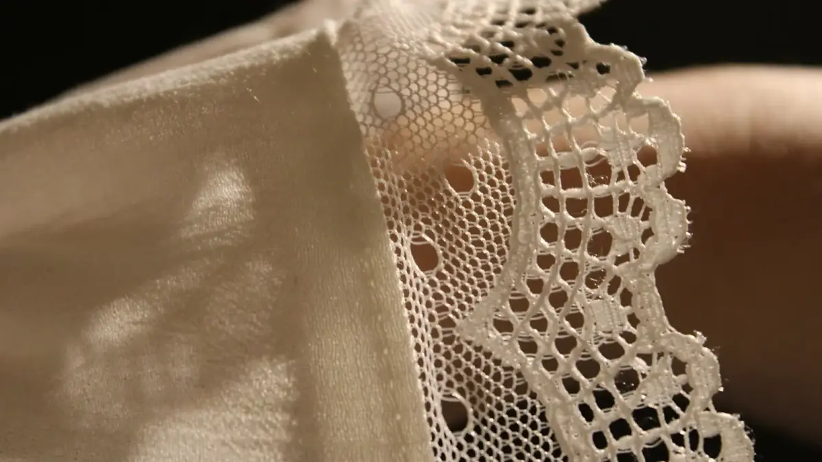 A close up of a person's hand holding a piece of lace