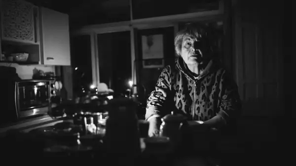 Woman sits in a dimly lit kitchen at night.