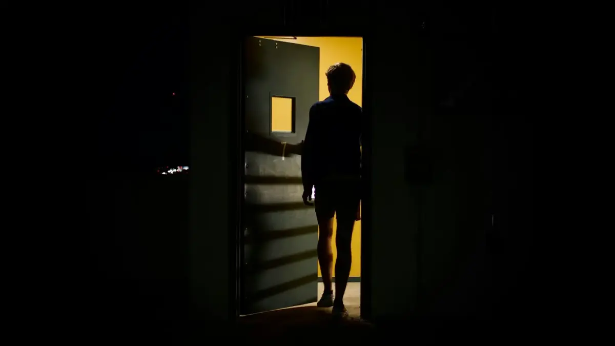 man in black jacket standing in front of white wooden door