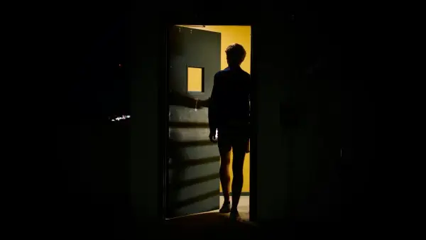 man in black jacket standing in front of white wooden door
