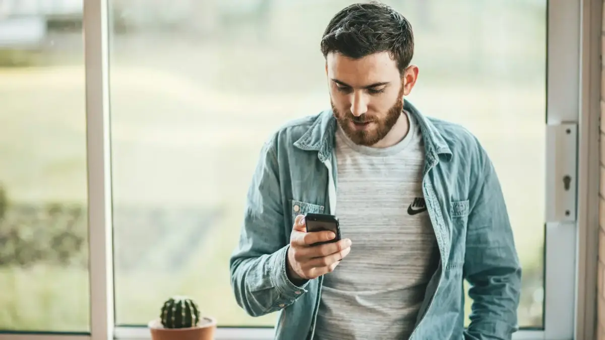 man holding a smartphone near the window