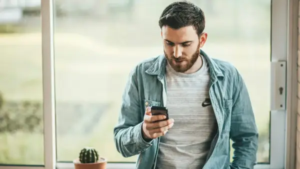 man holding a smartphone near the window