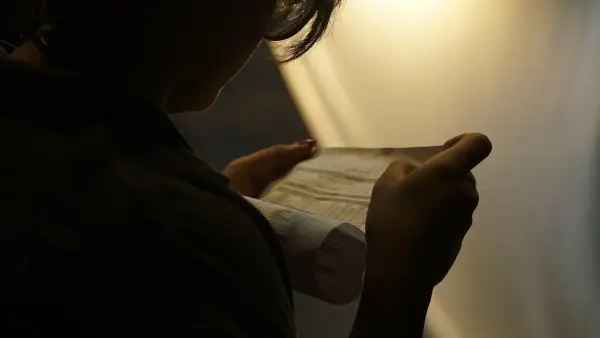 A person carefully examines a folded paper.