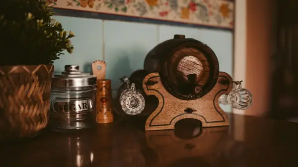 Decorative wooden barrel dispenser, glasses, and plant on a table
